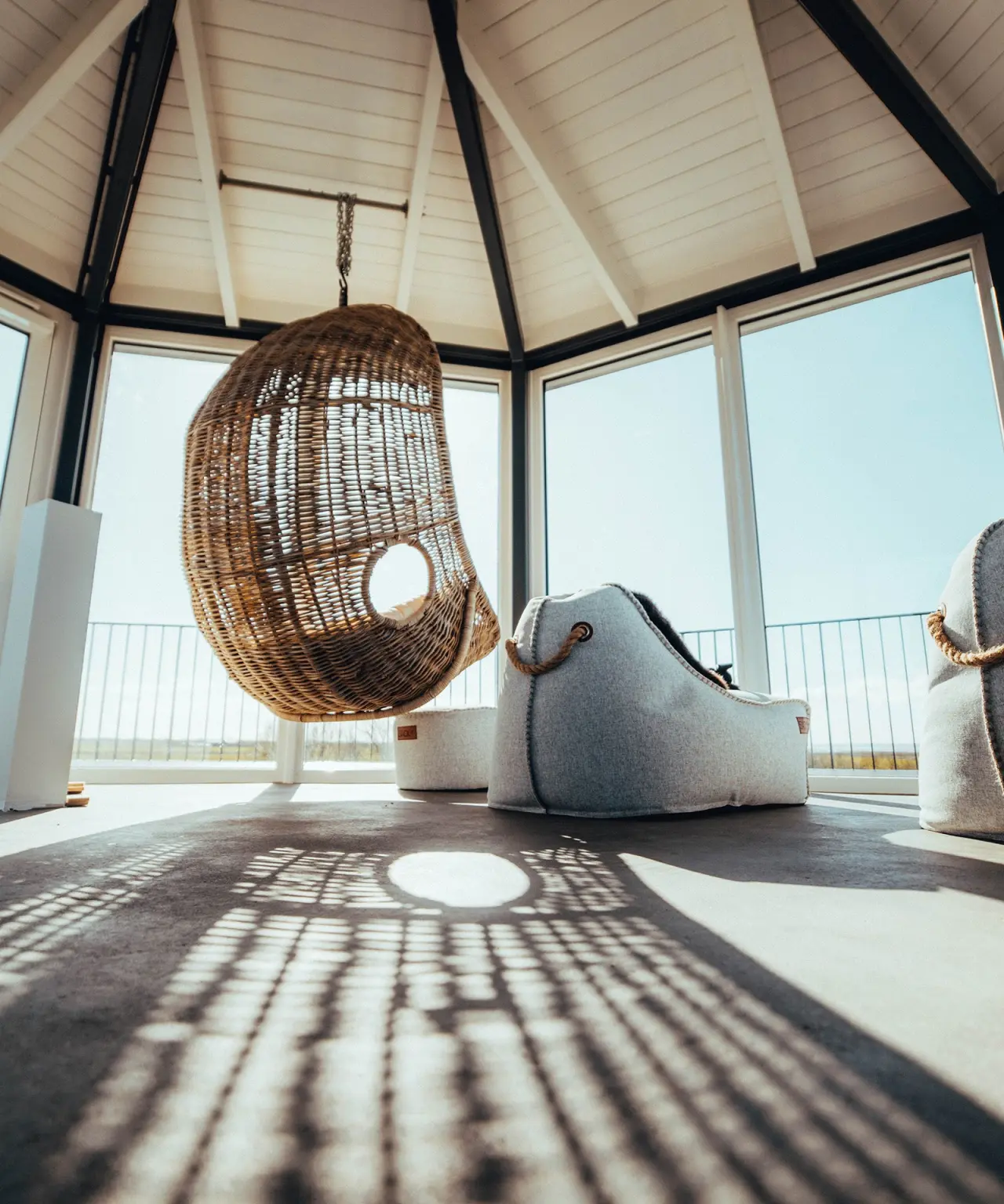 Lichtdurchfluteter Ruheraum mit Hängesessel und Panoramafenstern im Lundenbergsand Nordsee Hideaway und Spa.