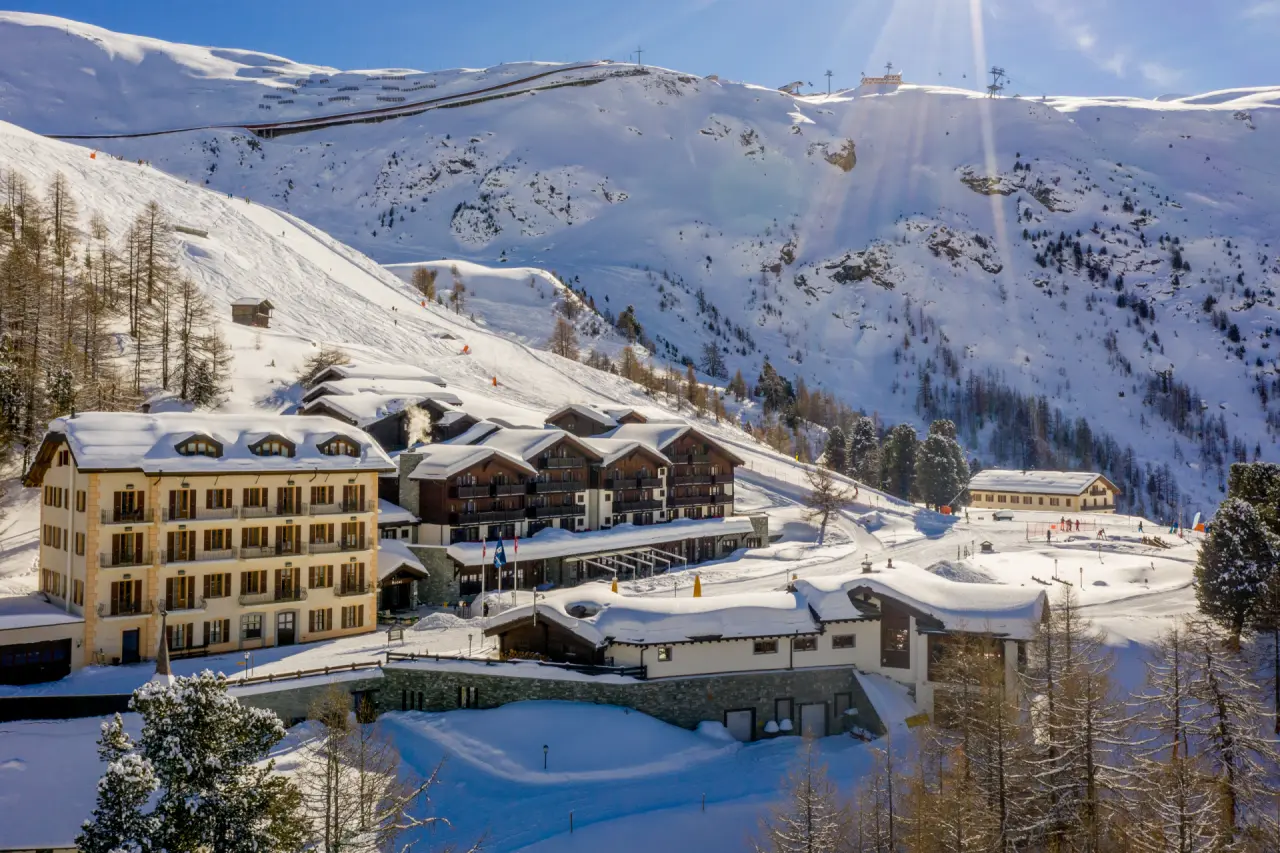 Riffelalp Resort 2222 m im Winter: Luxushotel in verschneiter Schweizer Berglandschaft mit Skipisten und Sonnenschein.