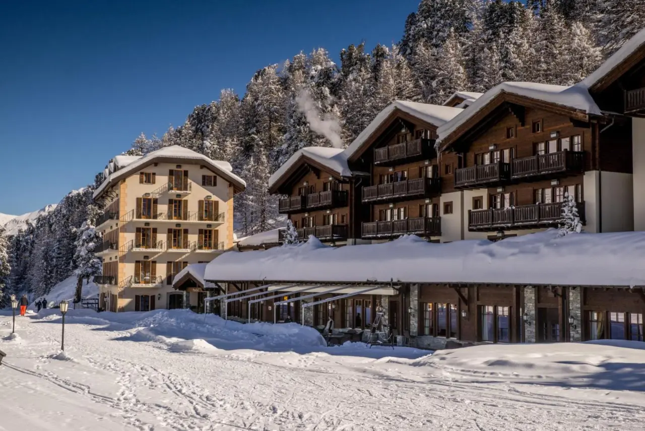 Winteransicht des luxuriösen Riffelalp Resort 2222 m in den Schweizer Alpen mit verschneiten Gebäuden und tiefblauem Himmel.