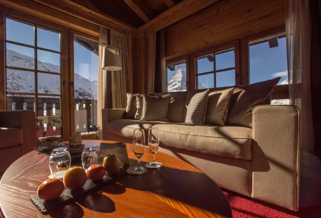 Gemütliches Wohnzimmer im Riffelalp Resort 2222 m mit Blick auf das Matterhorn und die verschneite Bergwelt.
