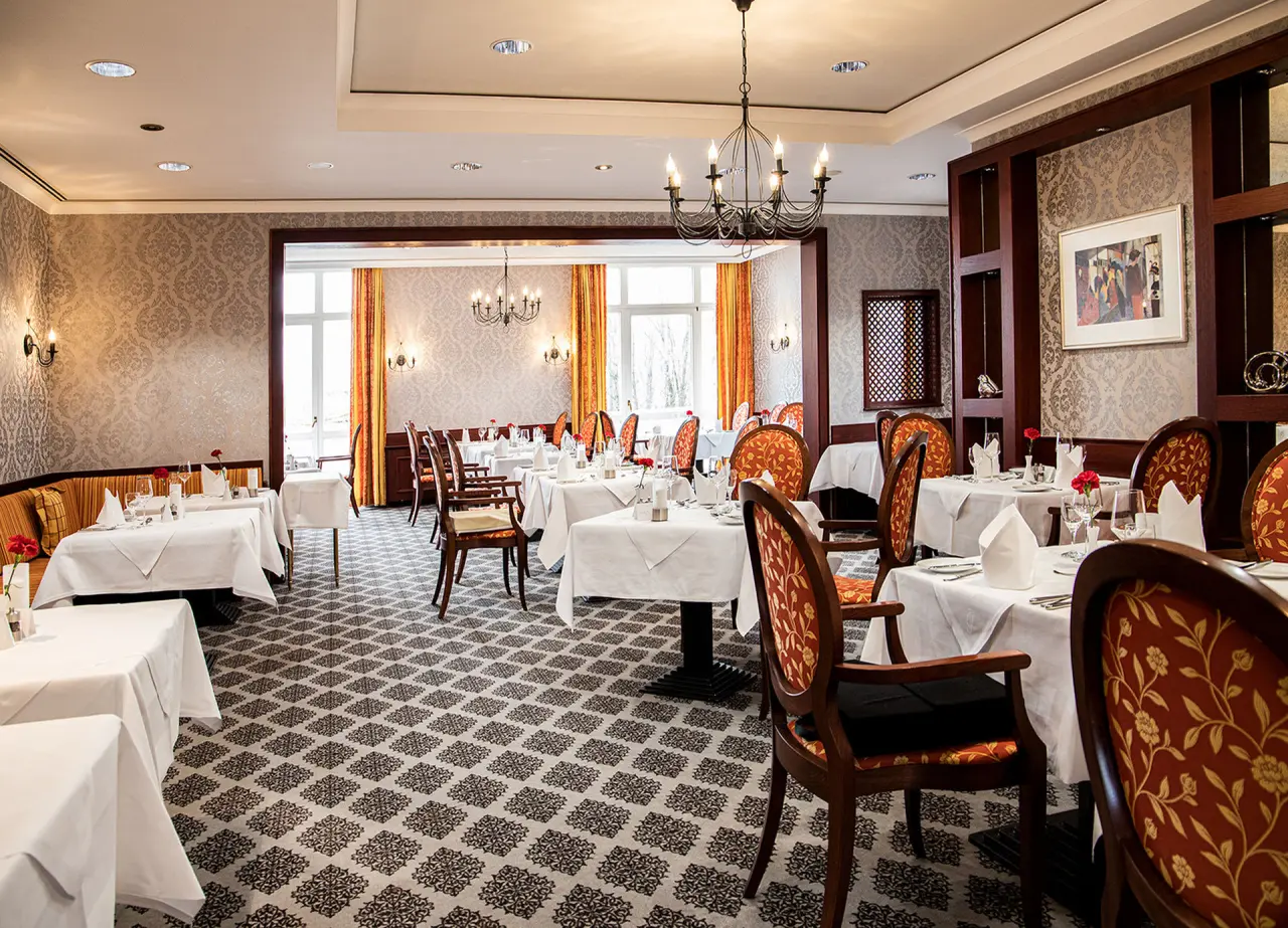 Elegantes Restaurant mit klassischem Interieur, gedeckten Tischen und Blick ins Grüne im Hotel St. Wolfgang*****.