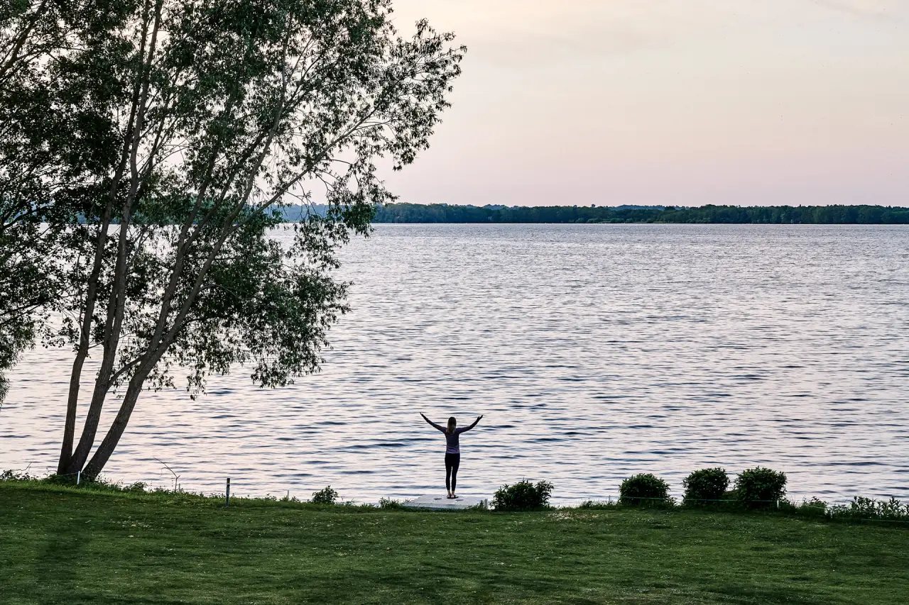 Person genießt die Ruhe am Seeufer bei Sonnenuntergang, umgeben von Natur am Designhotel Whitman.