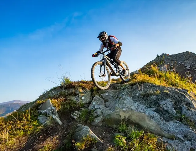 Mountainbiker auf felsigem Trail in den Bergen bei Ellmau. Aktiver Urlaub im Sporthotel Ellmau.
