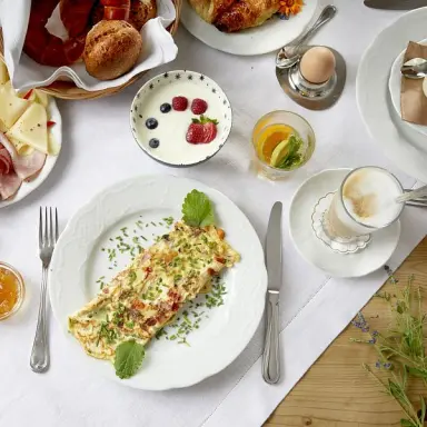 Reichhaltiges Frühstück mit Omelett, Joghurt, Gebäck und Kaffee im Sporthotel Ellmau.