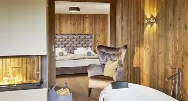 Gemütliches Hotelzimmer im Sporthotel Ellmau mit Kamin, Badewanne und Holzwänden für entspannte Momente.