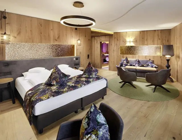 Modernes Doppelzimmer mit Holzelementen, bequemen Betten und Sitzbereich im Sporthotel Ellmau.