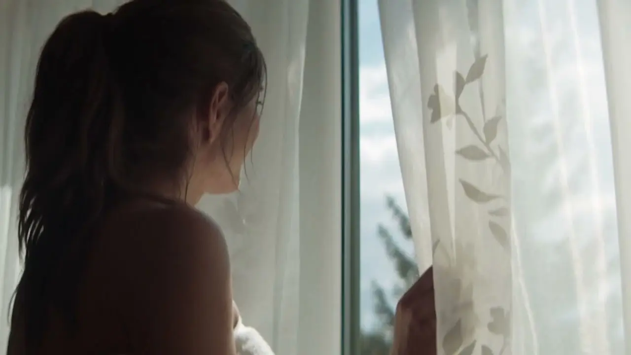 Frau genießt den Ausblick aus dem Fenster im Hotel Guglwald, ein Moment der Ruhe und Entspannung.