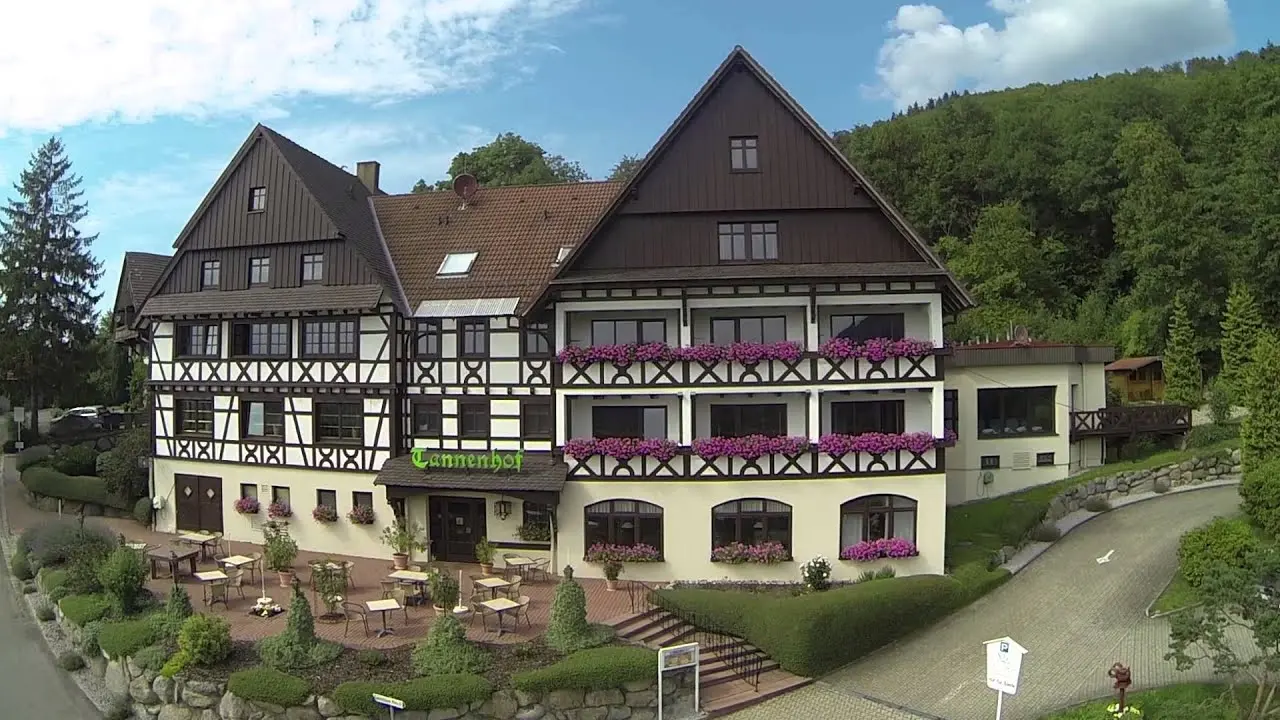Traditionelles Fachwerk-Hotel Relaxhotel Tannenhof mit blühenden Balkonen und Terrasse, umgeben von Wald.