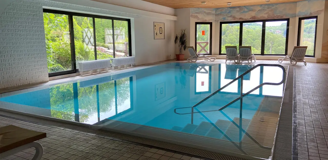 Innenpool mit grossen Fenstern und Blick ins Grüne im Relaxhotel Tannenhof. Entspannung pur im Schwimmbadbereich.