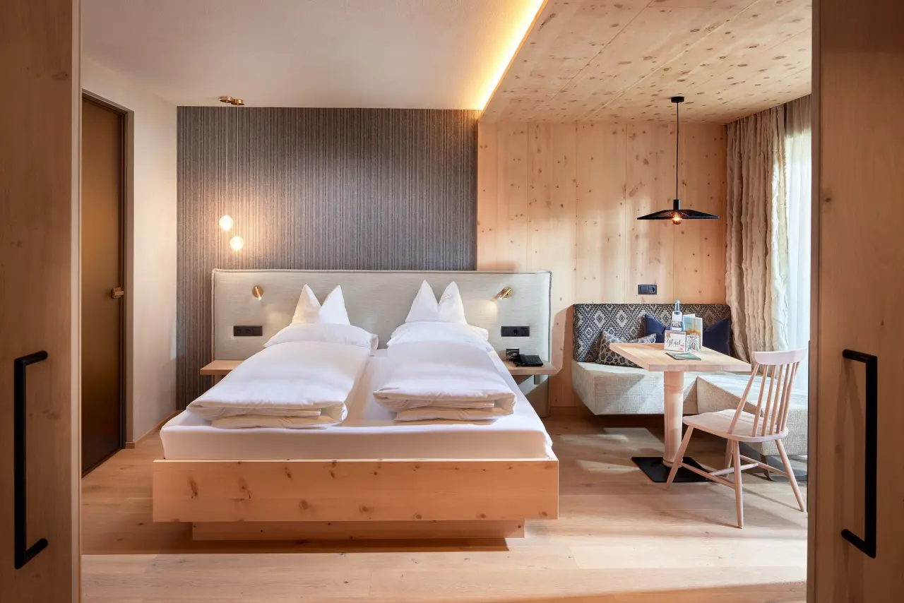 Modernes Doppelzimmer mit Holzelementen und gemütlicher Sitzecke im Hotel Neue Post