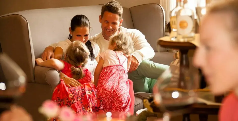 Glückliche Familie mit zwei Kindern entspannt auf einem Sofa im gemütlichen Ambiente von Schloss Basthorst.