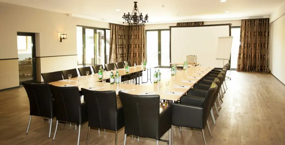 U-förmiger Konferenztisch mit Stühlen und Beamer-Leinwand im Tagungsraum des Schloss Basthorst.
