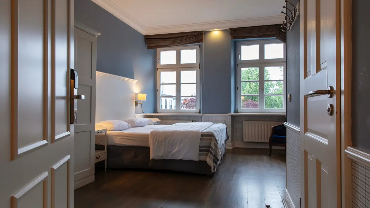 Gemütliches Hotelzimmer im Schloss Basthorst mit Doppelbett, blauer Wand und Blick ins Grüne.