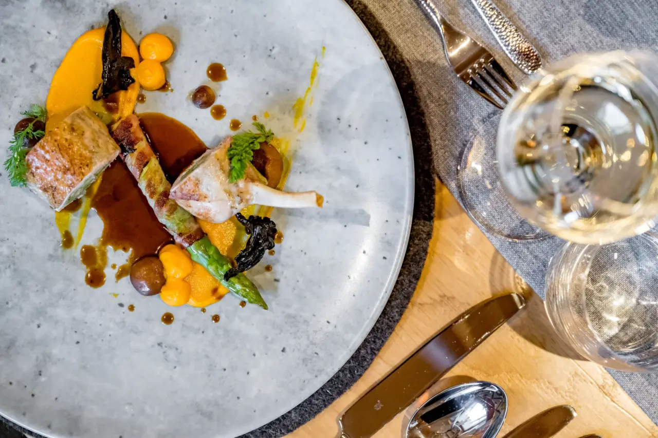 Exquisit angerichtetes Gourmet-Gericht mit Fleisch und Gemüse im Restaurant des Naturhotel Alpenblick.