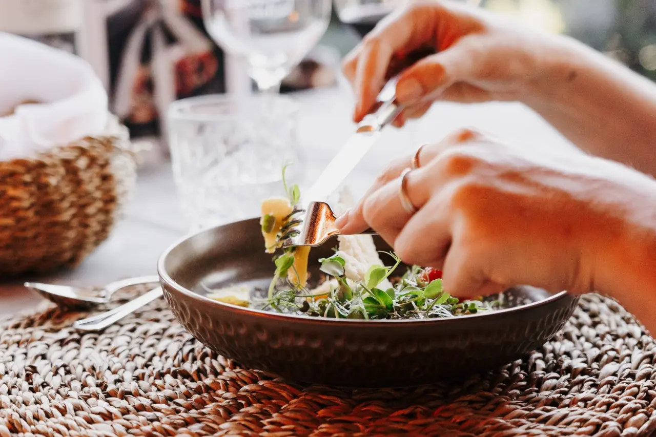 Gast genießt eine frische Mahlzeit im Restaurant des Boutiquehotel Haidachhof, mit Fokus auf das Gericht und die Hände.