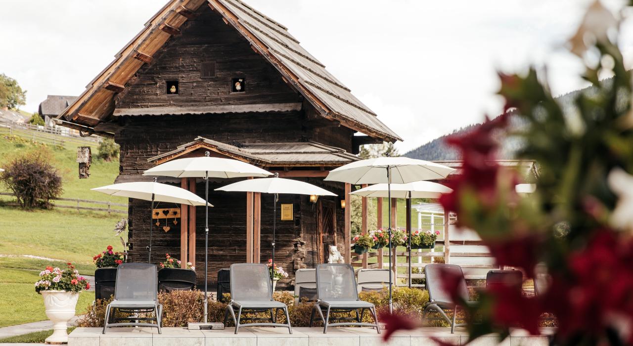 Hotel Pulverer in Bad Kleinkirchheim – Traditionelles Holzhaus mit Liegestühlen im Garten | Wellnesshotel Kärnten
