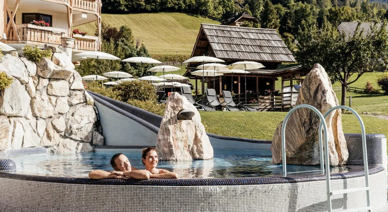 Hotel Pulverer in Bad Kleinkirchheim – Paar entspannt im Außenpool mit Bergblick | Wellnesshotel Kärnten