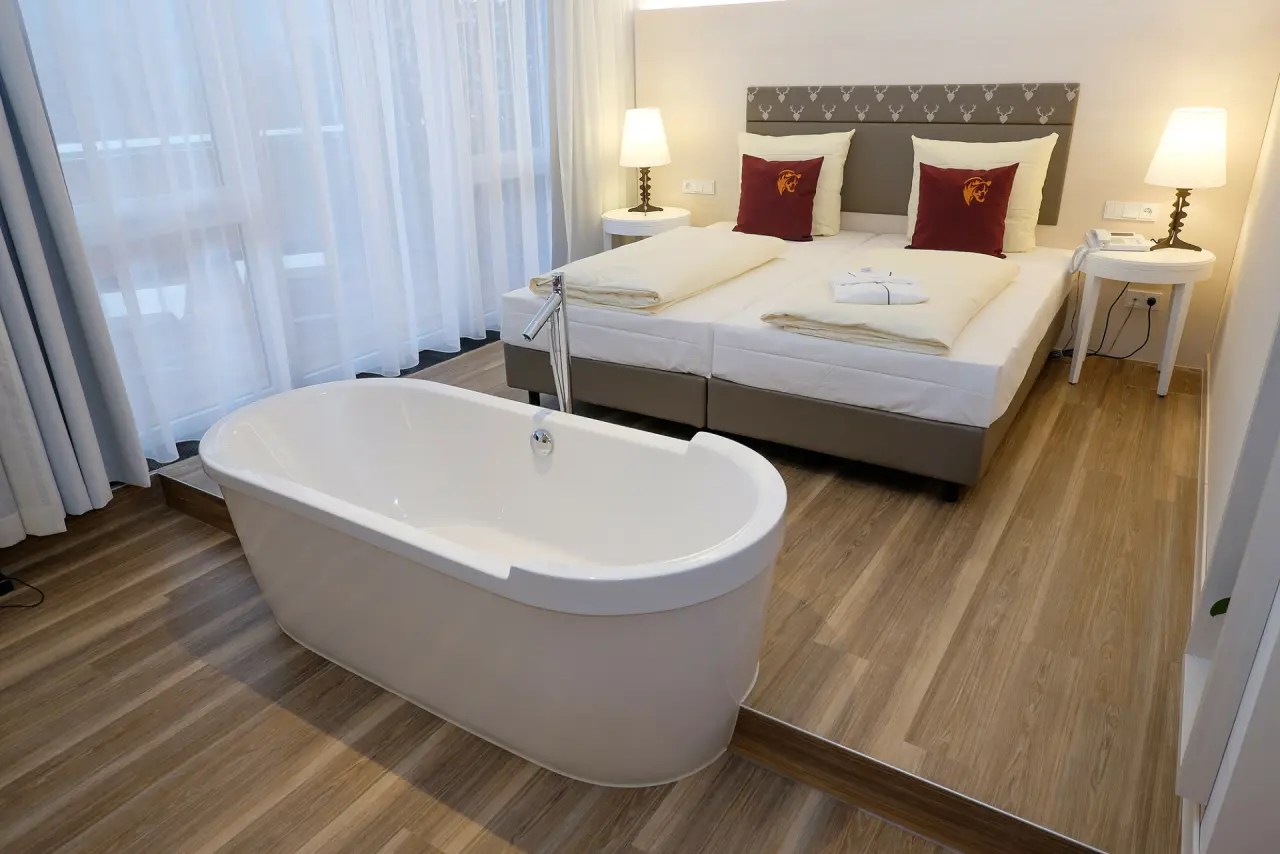 Modernes Hotelzimmer im Hotel Bären Titisee mit Doppelbett und freistehender Badewanne am Fenster