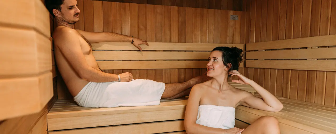Entspanntes Paar in der finnischen Sauna des Hotel Bären Titisee. Warme Holzsauna für Wellness und Erholung.