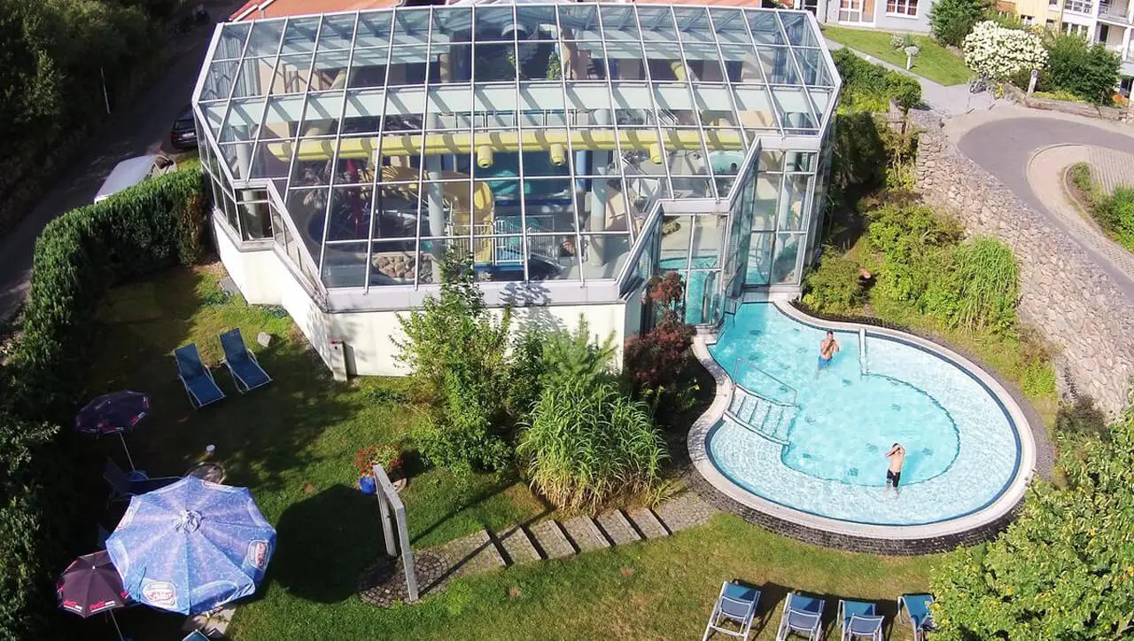 Luftaufnahme des grossen Glas-Poolkomplexes und des Aussenpools mit Gästen im Precise Resort Marina Wolfsbruch.