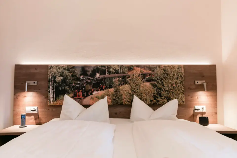 Gemütliches Doppelzimmer im Hotel Panoramic mit Holzkopfteil, Leselampen und Wandbild einer Dampflok.