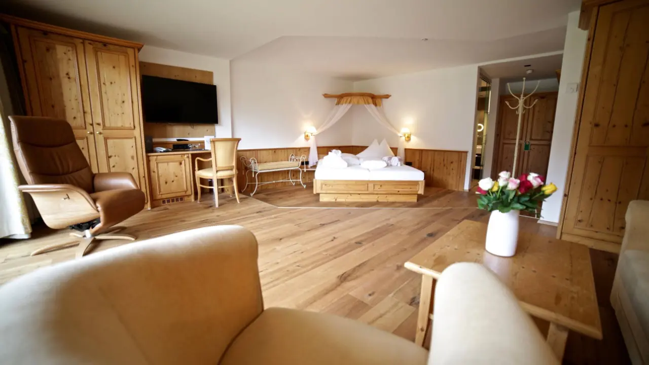 Gemütliches Doppelzimmer im Alpinhotel Jesacherhof mit Holzmöbeln, Himmelbett und Sitzbereich.