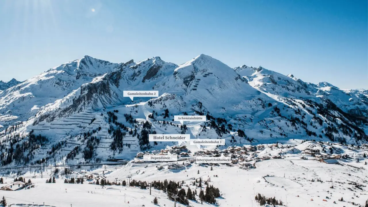 Panoramablick auf das Hotel Schneider in der verschneiten Alpenlandschaft von Obertauern, umgeben von Skipisten.