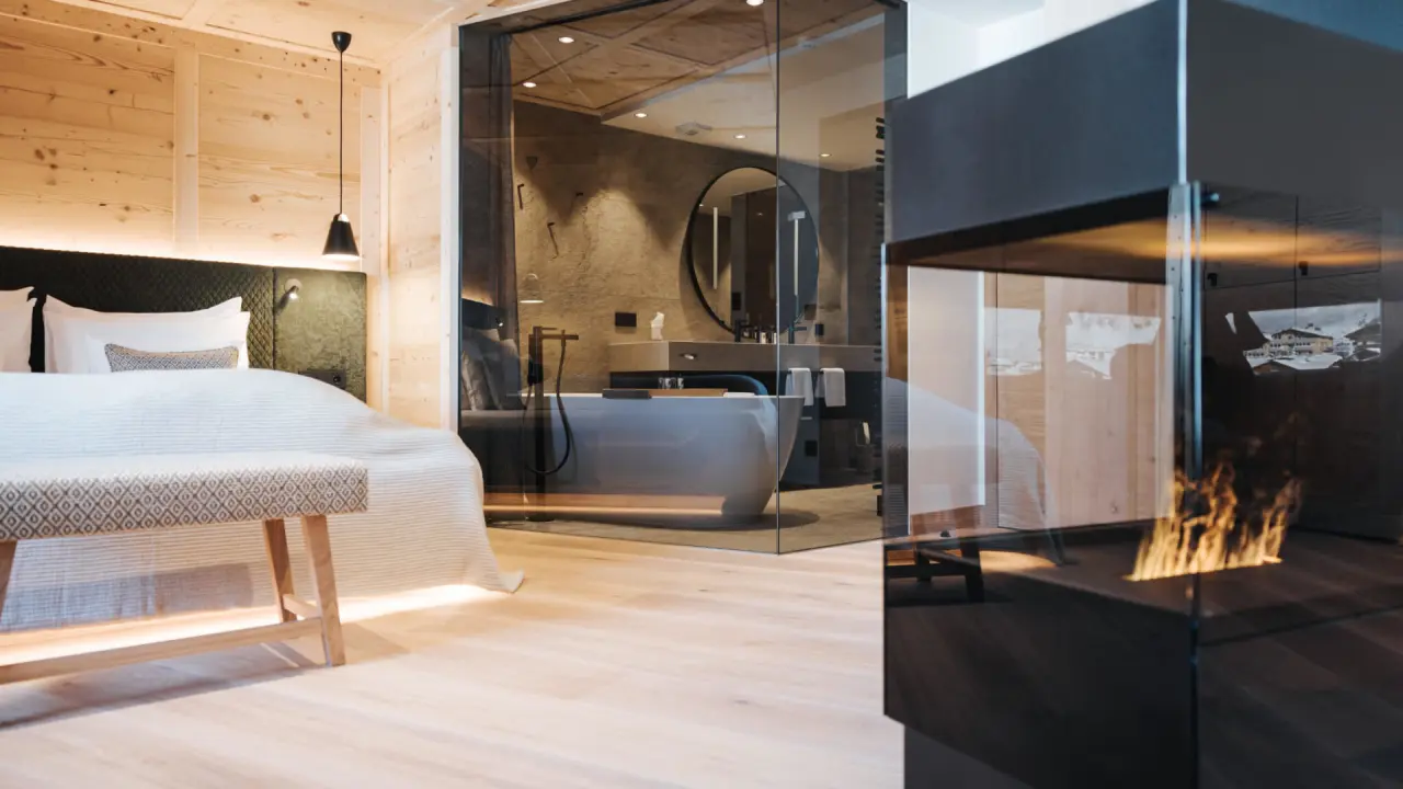 Luxuriöses Hotelzimmer im Hotel Schneider mit freistehender Badewanne, modernem Kamin und alpiner Holzgestaltung.