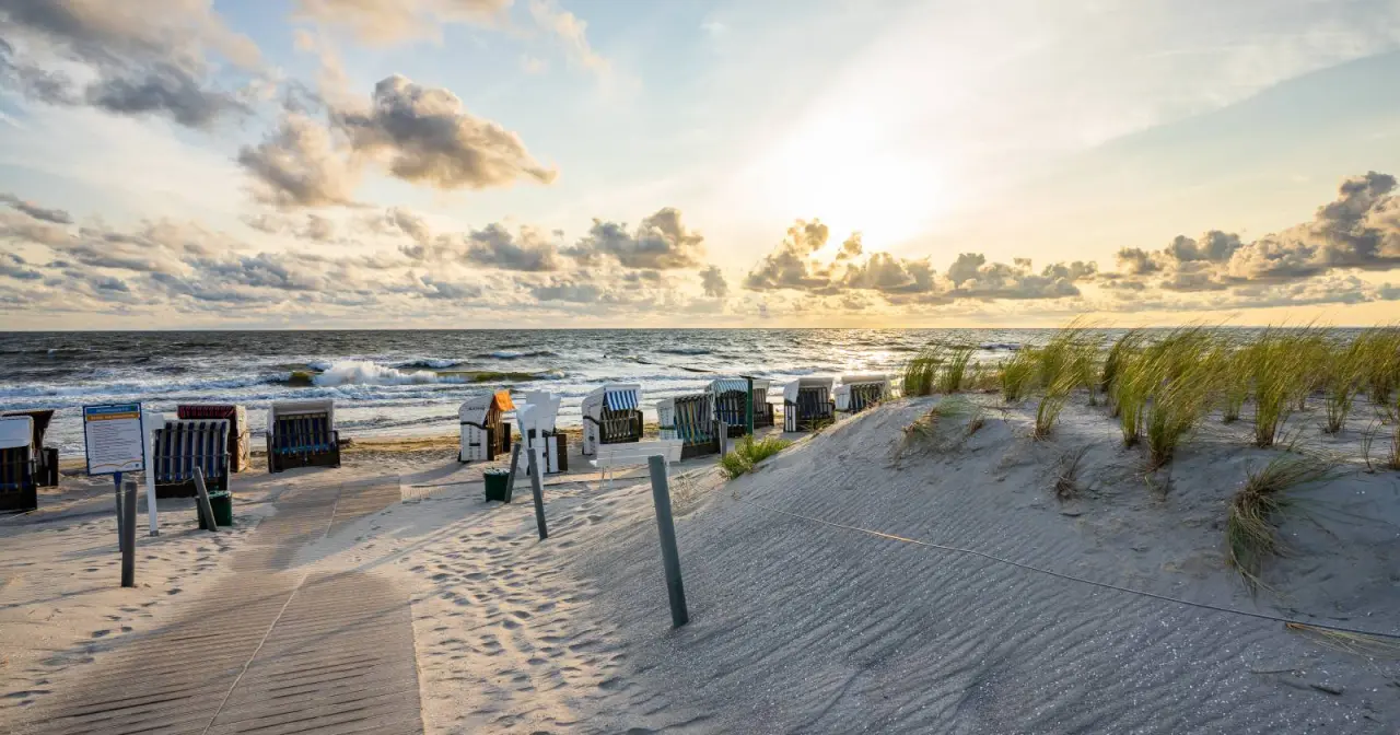 Sonnenuntergang am Strand mit Strandkörben und Dünen vor dem Strandhotel Seerose an der Ostsee.
