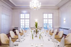Eleganter Speisesaal oder Veranstaltungsraum im ATLANTIC Grand Hotel Travemünde, festlich gedeckt mit Kronleuchter.