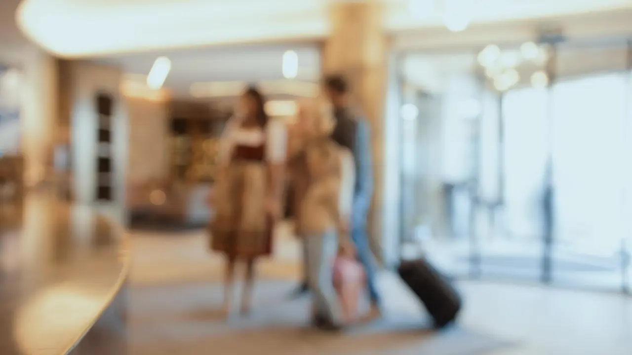 Verschwommene Szene in der Lobby des Hotel Alpin Spa Tuxerhof mit ankommenden Gästen und Gepäck.