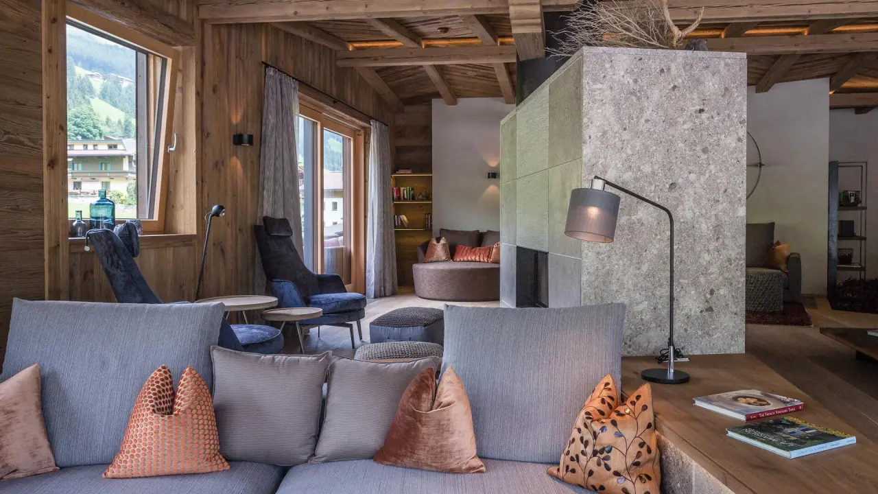 Gemütliche Lounge mit Holzelementen und Kamin im Hotel Alpin Spa Tuxerhof. Einladender Bereich zum Entspannen.