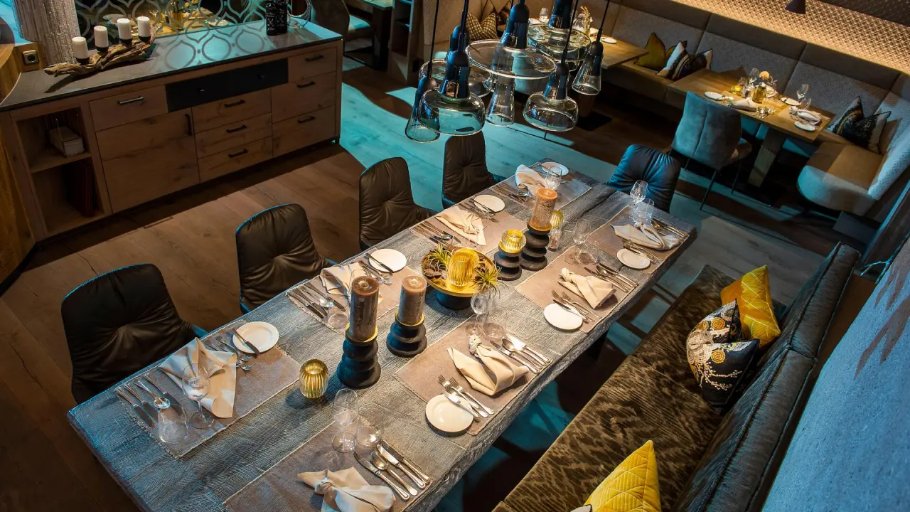 Elegantes Restaurant mit langer Holztischtafel und gemütlicher Beleuchtung im Hotel Alpin Spa Tuxerhof.