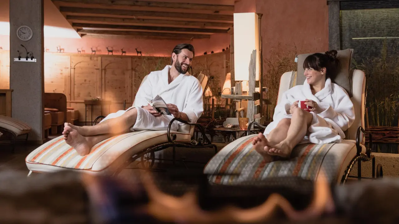 Entspannendes Paar in Bademänteln auf Liegen im alpinen Wellnessbereich des Hotel Alpin Spa Tuxerhof.
