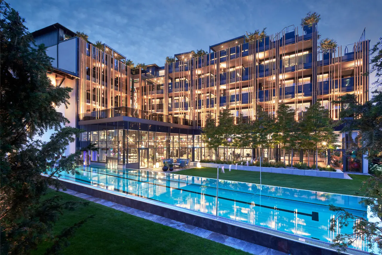 Beleuchtetes 5-Sterne Wellness- & Sporthotel Jagdhof bei Nacht mit modernem Aussenpool und stilvoller Architektur.