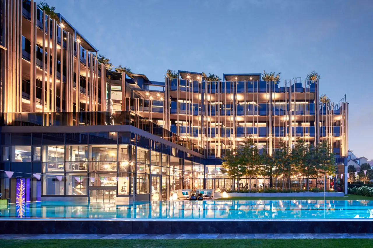 Abendansicht des 5-Sterne Wellness- & Sporthotels Jagdhof mit beleuchtetem Aussenpool und moderner Architektur.