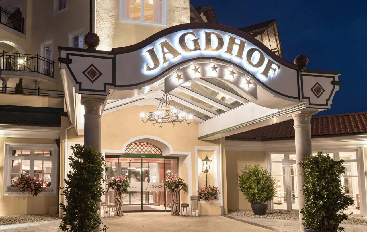 Beleuchteter Haupteingang des 5-Sterne Wellness- & Sporthotels Jagdhof bei Nacht.