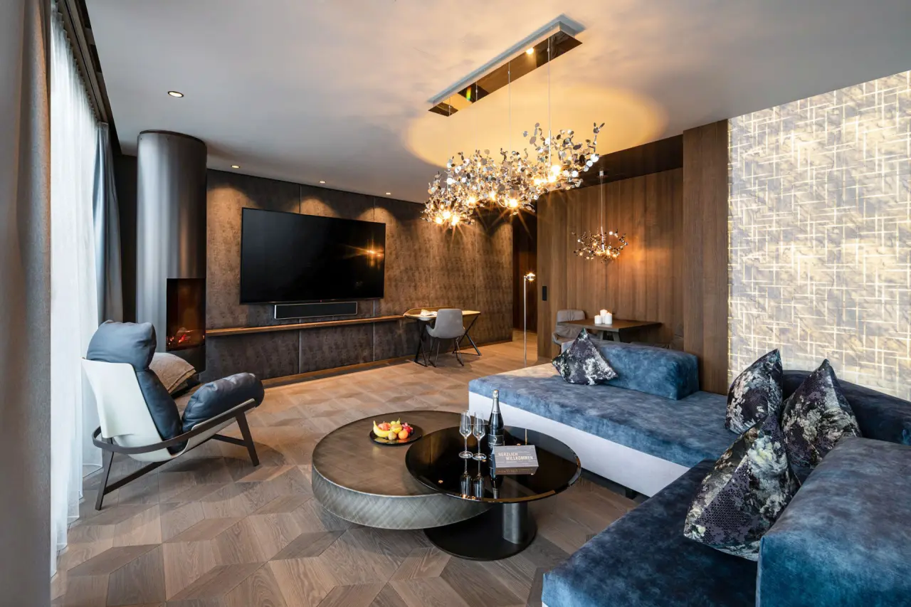 Luxuriöse Suite im 5-Sterne Wellness- & Sporthotel Jagdhof mit modernem Wohnbereich, Kamin und stilvoller Einrichtung.