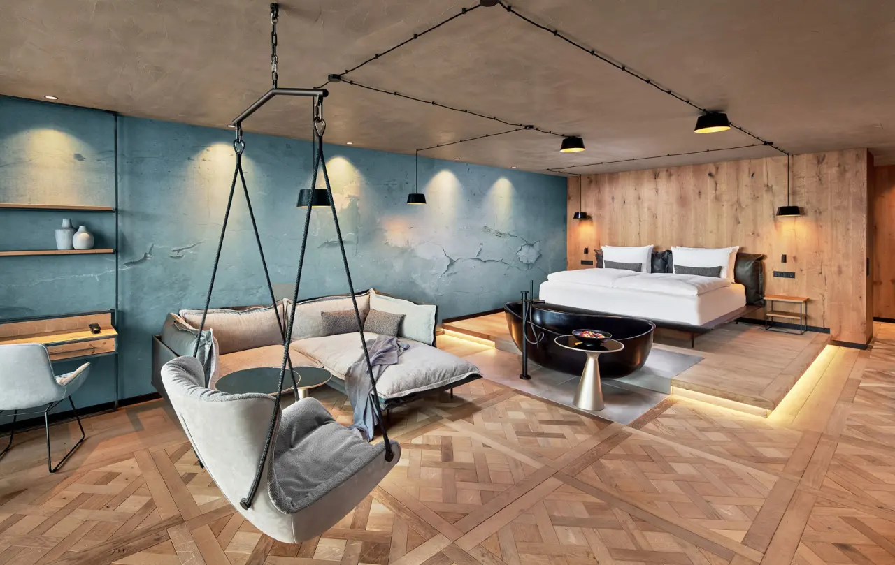 Modernes Hotelzimmer mit freistehender Badewanne, Hängesessel und Doppelbett im 5-Sterne Wellness- & Sporthotel Jagdhof.