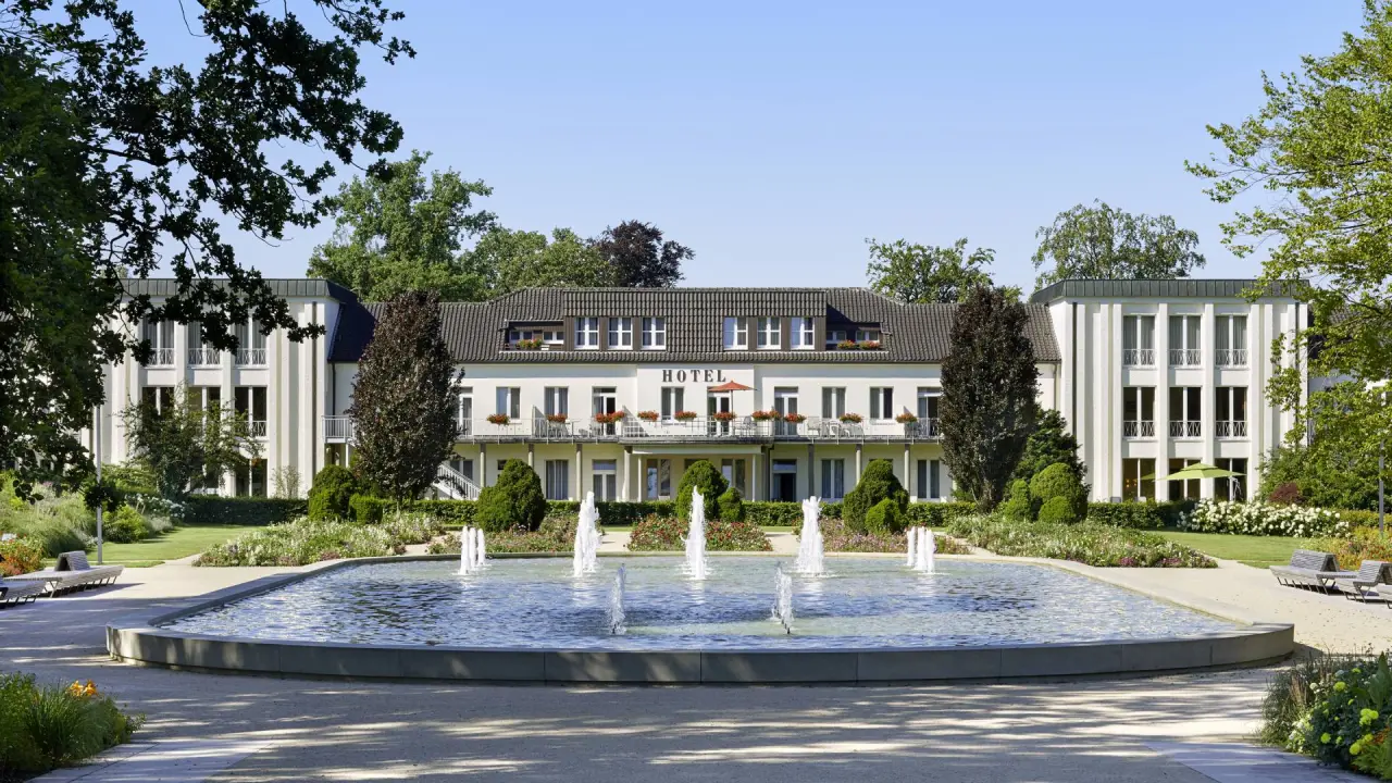 Elegante Aussenansicht des Best Western Premier Park Hotel & Spa mit Brunnen und gepflegtem Garten unter blauem Himmel.