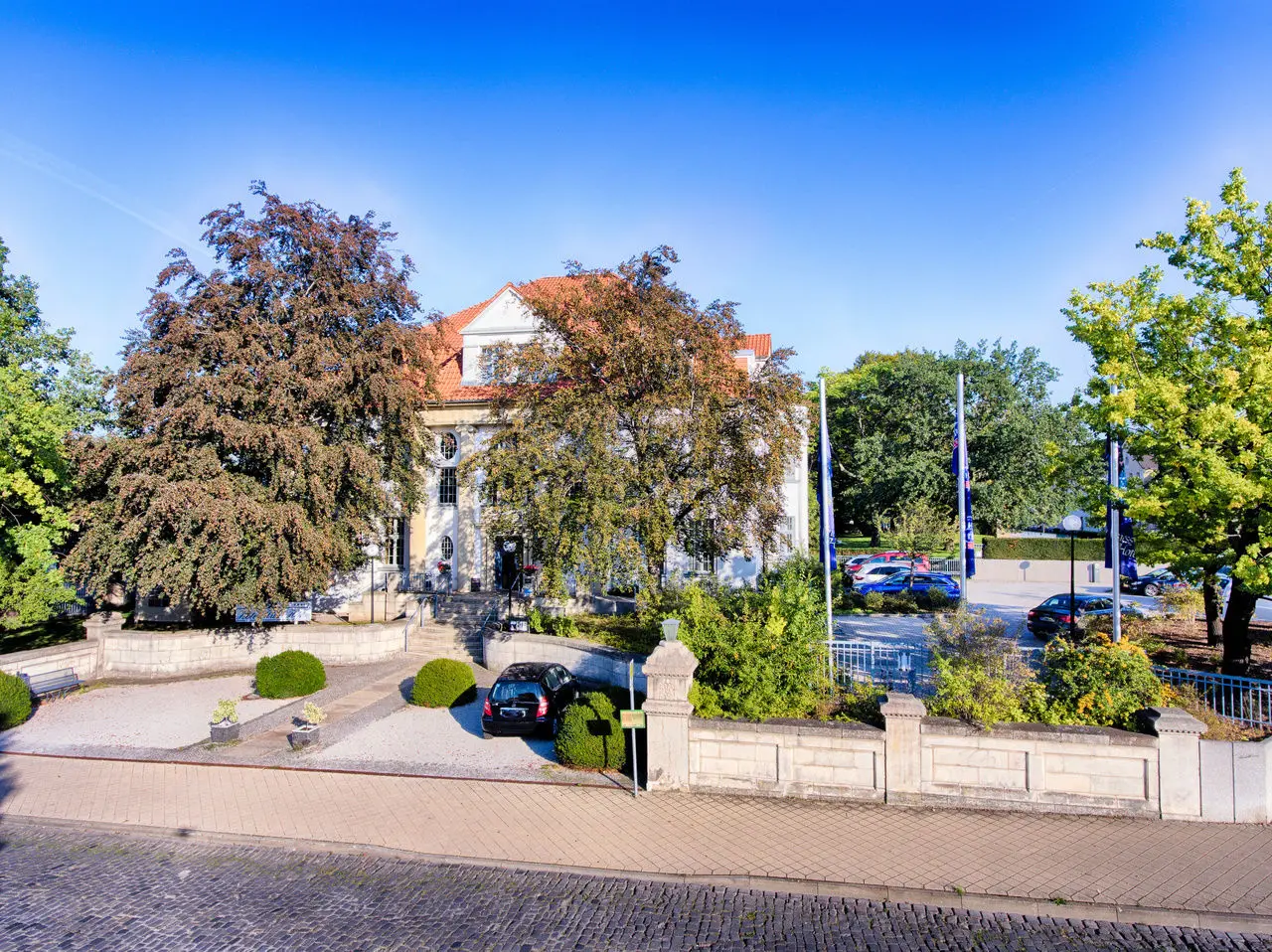 Aussenansicht des Hotels Villa Heine mit historischer Architektur, umgeben von Bäumen und einem gepflegten Vorgarten.