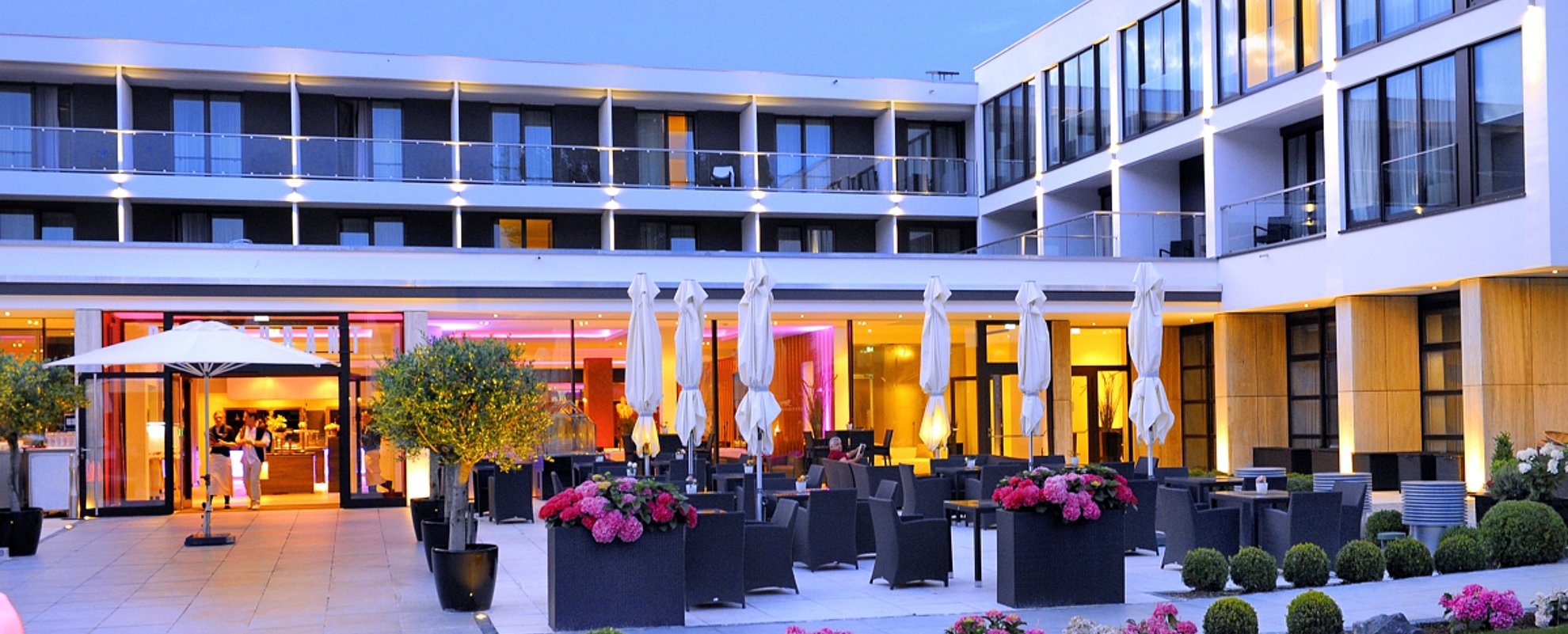 Schlosshotel Bad Wilhelmshöhe in Kassel – Elegante Außenterrasse mit Tischen und Schirmen am Abend | Wellnesshotel Hessen