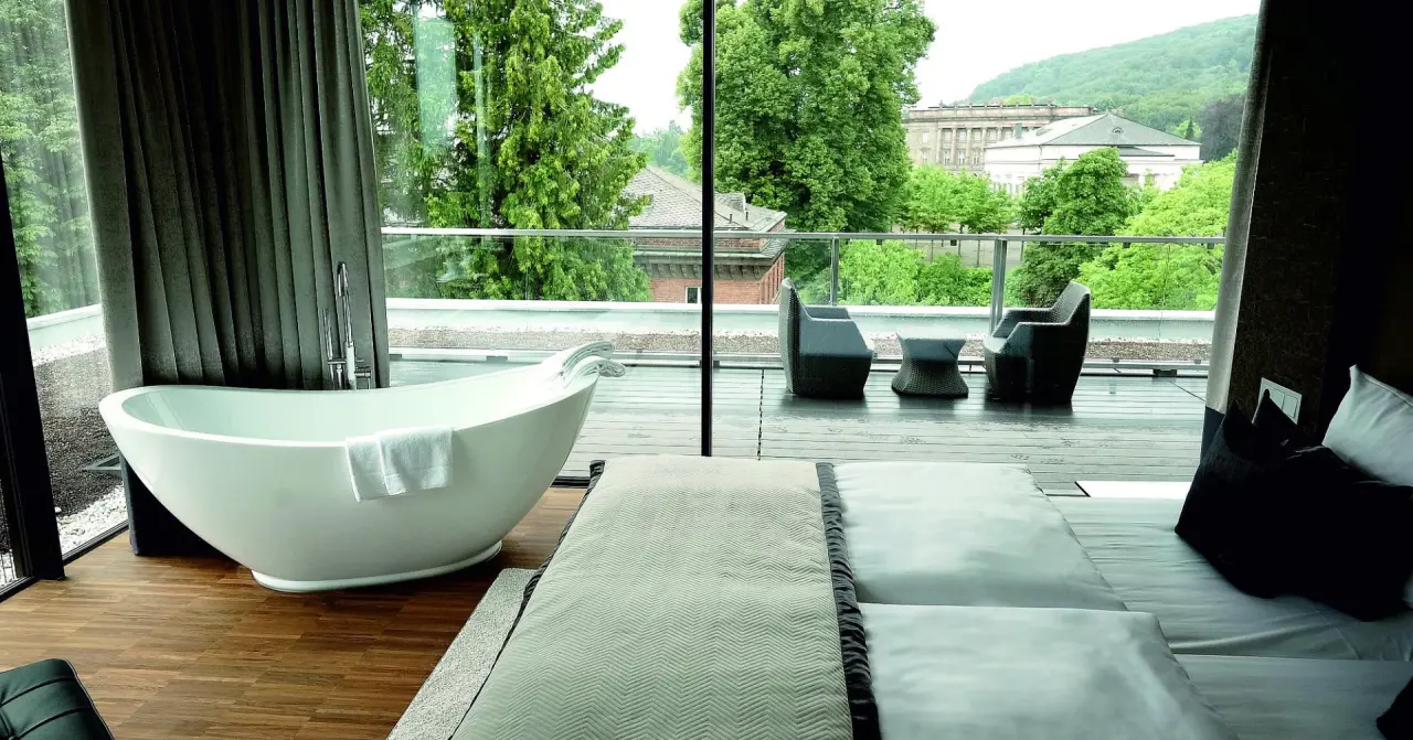 Luxuriöses Hotelzimmer im Schlosshotel Bad Wilhelmshöhe mit freistehender Badewanne, Balkon und Blick ins Grüne.