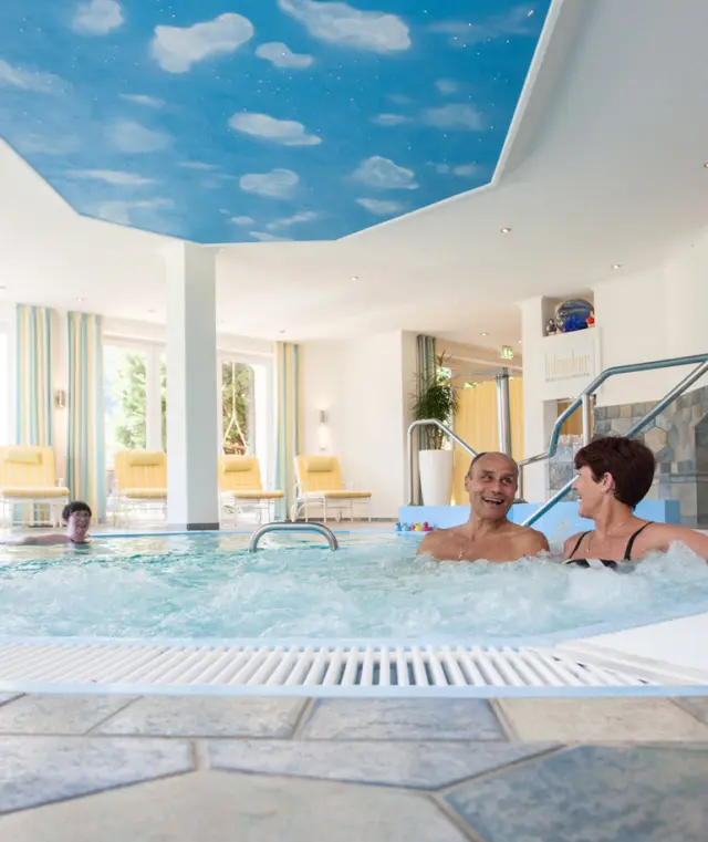 Gäste genießen den Whirlpool mit Wolkendecke im Wellnessbereich des Hotel Haus Hilmeke.