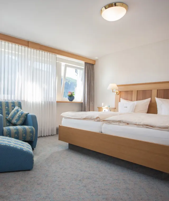 Gemütliches Doppelzimmer mit Holzbett und Sitzbereich im Hotel Haus Hilmeke.
