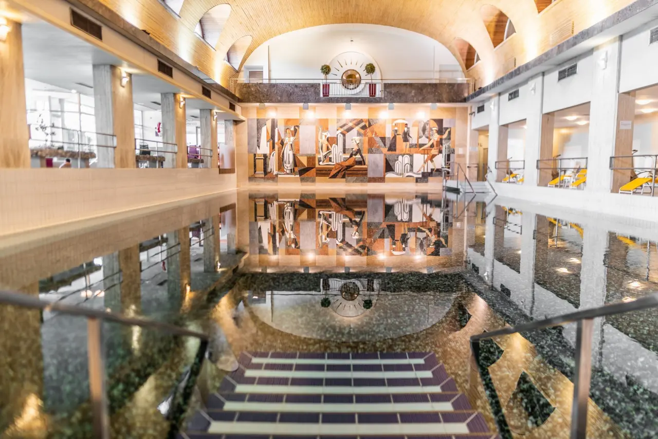 Grosszügiger Innenpool mit kunstvoller Wandmalerei und Holzdecke im Hotel Warmbaderhof *****. Ideal für Entspannung.