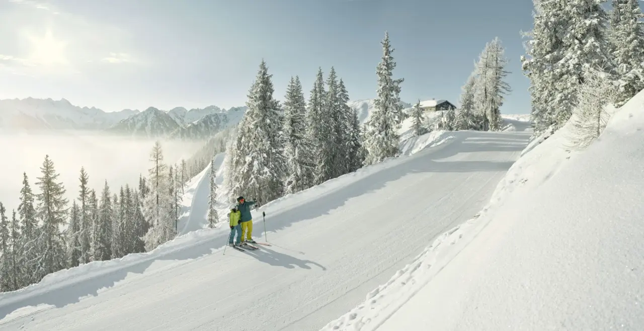 Skifahrer auf frisch präparierter Piste mit verschneiten Bäumen und Bergpanorama im Sporthotel Royer Schladming.