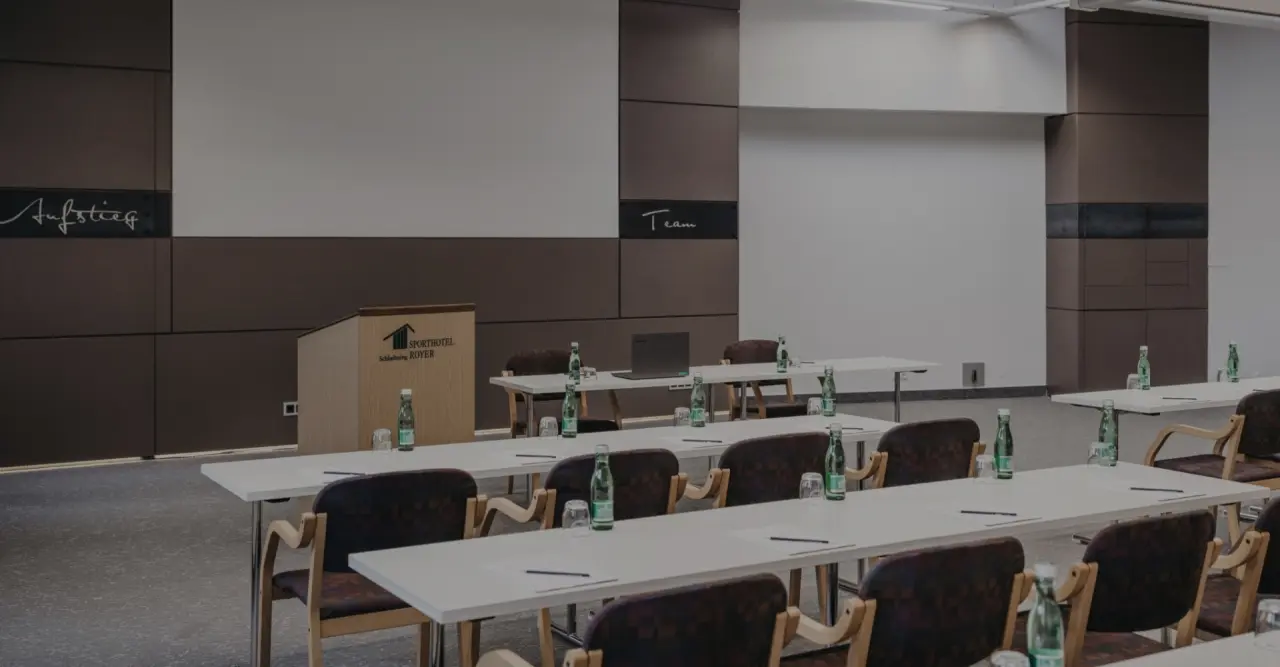 Moderner Konferenzraum im Sporthotel Royer Schladming mit Rednerpult, Tischen und Stühlen für Tagungen und Seminare.
