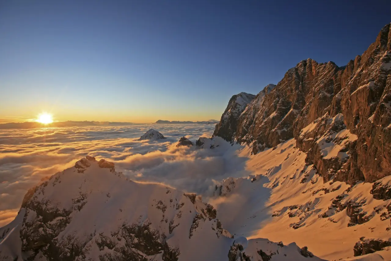 Spektakulärer Sonnenuntergang über einem Wolkenmeer in den verschneiten Bergen bei Schladming, nahe dem Sporthotel Royer.