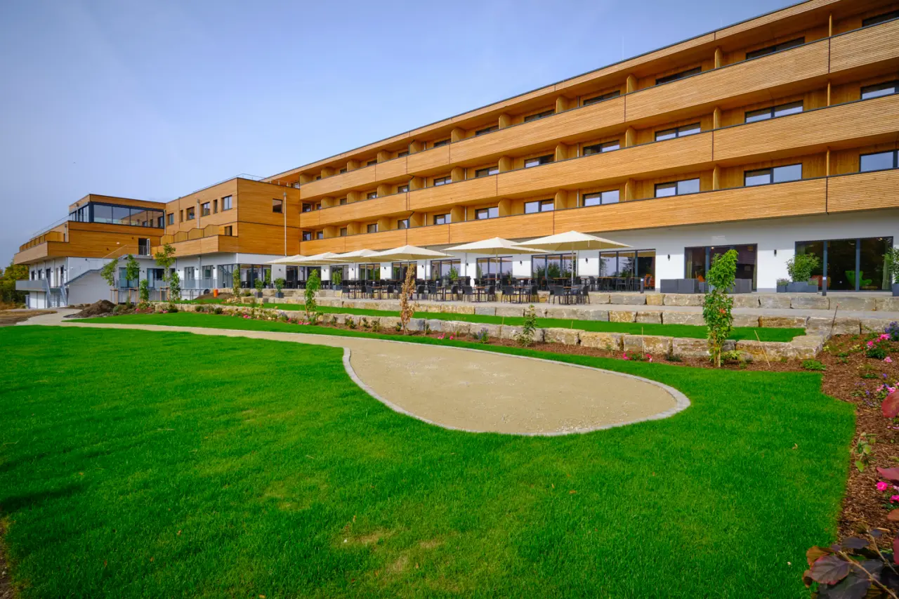 Aussenansicht des sonnenhotel WEINGUT RÖMMERTH mit moderner Holzfassade, grosser Sonnenterrasse und gepflegtem Garten.
